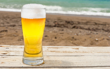 Pint of beer by beach with sea in background