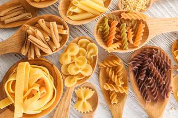 Wooden spoons with uncooked pasta on table