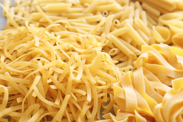 Different uncooked pasta as background, closeup
