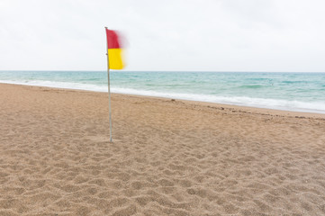 Fototapeta na wymiar Red and yellow warning flag on a deserted beach