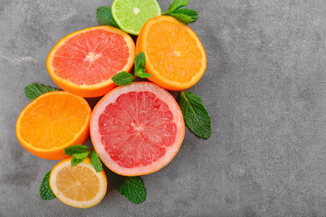 Ripe citrus fruits and mint on grey background