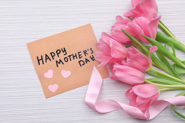 Bouquet of flowers and greeting card for Mother's Day on wooden background
