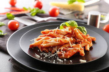 Plate of tasty pasta with tomato sauce on table