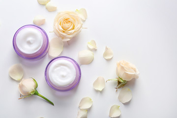 Fototapeta na wymiar Jars with skin care cosmetics and flowers on white background