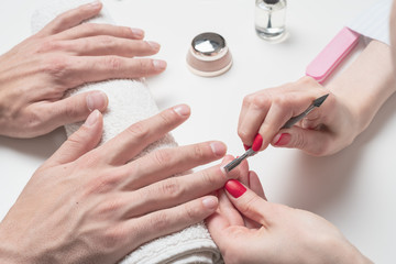 Men's manicure. hands of the beautician treated cuticle of male hands using pusher, scraper