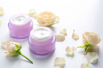 Obraz na płótnie Canvas Jars with skin care cosmetics and flowers on white background