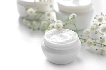 Fototapeta na wymiar Jar with cream and flowers on white background. Skin care cosmetics