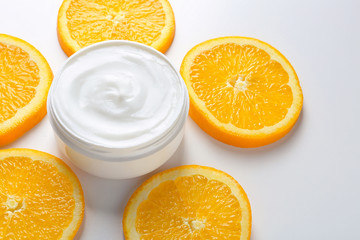 Jar with cream and sliced orange on white background. Skin care cosmetics