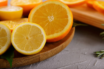 Wooden board with ripe citrus fruits on table