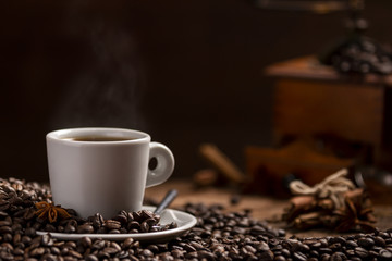 Cup of coffee with coffee beans and grinder on wooden table