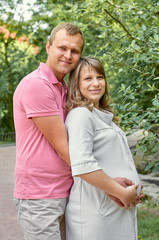Obraz premium Pregnant woman with husband man in park nature family concept