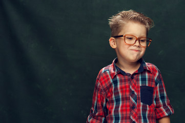 Fototapeta premium Portrait of Cute funny boy with stylish shirt with eyeglasses on dark green background