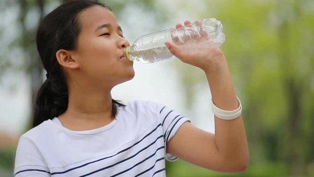 asian teenager drinking water in plastic bottle