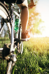 Detail of cyclist man feet riding mountain bike on outdoor trail deep grass