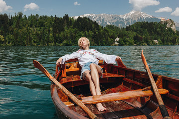 beautiful young woman resting in boat at tranquil mountain lake, bled, slovenia