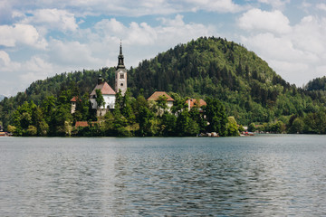 majestic view of mountains covered with green trees, calm lake and old buildings, bled, slovenia