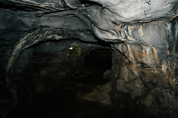 Beautiful cave. View from inside dark dungeon. Textured walls of cave. Background image of underground tunnel. Dampness inside cave. Lighting inside cave for excursions.