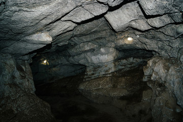 Beautiful cave. View from inside dark dungeon. Textured walls of cave. Background image of underground tunnel. Dampness inside cave. Lighting inside cave for excursions.