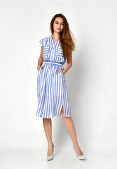 Young beautiful woman posing in new blue stripes casual summer dress on grey 
