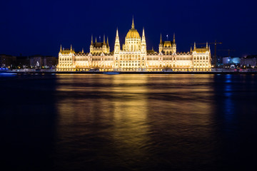 Fototapeta na wymiar Illuminated Budapest parliament building at night with dark sky and reflection in Danube river