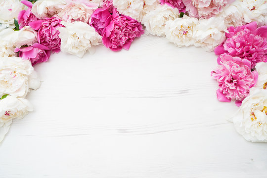 White and pink peonies on white wooden background. Holiday background, copy space, top view