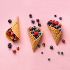 Frozen berries - strawberry, blueberry, blackberry, raspberry in waffle cones on pink background. Top view. Banner. Pattern for minimal style. Pop art design, creative concept
