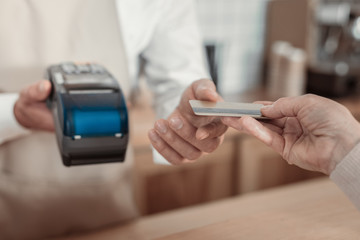 Terminal equipment. Competent worker using modern gadget while getting money for order