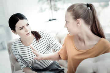 Stop talking. Unsatisfied teen girl stretching hand while concerned female psychologist looking at her and frowning