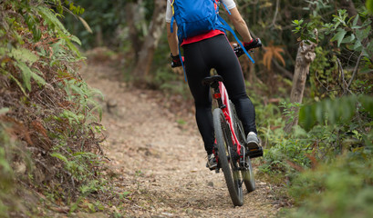 Naklejka premium cyclist woman legs riding mountain bike on outdoor trail in forest