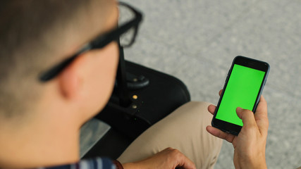 man's hands holding cell telephone while standing in modern airport hall