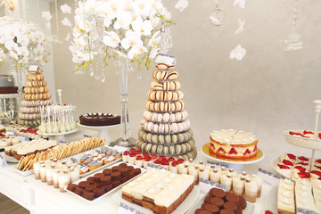 luxury wedding catering, table with modern desserts, cupcakes, sweets with fruits. delicious candy bar at expensive wedding reception.