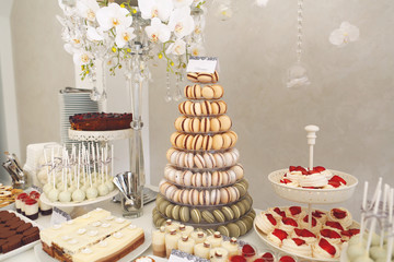 luxury wedding catering, table with modern desserts, cupcakes, sweets with fruits. delicious candy bar at expensive wedding reception.
