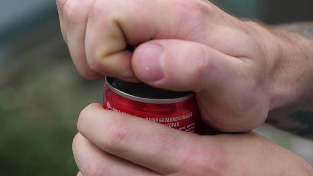 Young guy open up a can of cola drink closeup