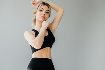 Obraz premium portrait of young athletic woman in black sportswear posing isolated on grey