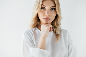 portrait of beautiful blond woman in white clothing posing on white backdrop