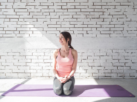 Portrait of smiling woman before exercises. Brunette with fit body on yoga mat. Healthy lifestyle and sports concept. Series of exercise poses.
