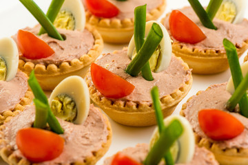 Three baguette slices with liver and apple pate and a thin tomato slice on top. Shallow DOF