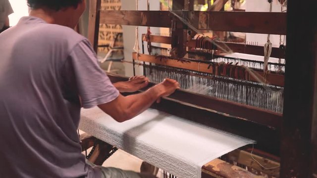 Indonesian man weaving white towel with foot-treadle loom machine. Shot with Sony a7s and Atomos Ninja Flame in Indonesia