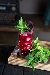 Red cocktail drink in a glass with mint leaves and ice, fresh juice and liquor