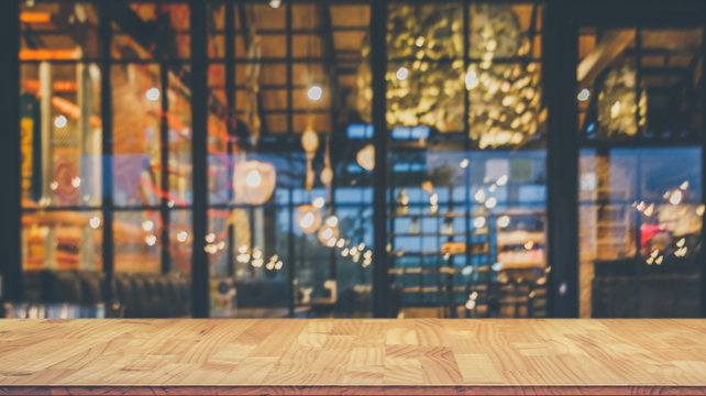 Image of wooden table in front of abstract blurred restaurant lights background