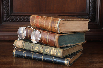 old books piled on an antique wooden furniture