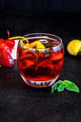 Red cocktail with ice and orange on black background