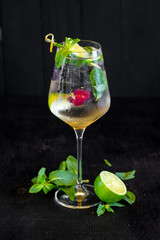 Fresh cold cocktail with lime and cherry on black background