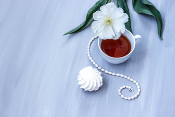 Cup of black tea, marshmallow, and white Tulip on grey wooden background