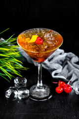 Sweet orange cocktail with cherry and ice on black background