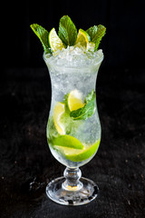 Fresh mojito with ice and lime on black background