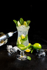 Fresh mojito with ice and lime on black background