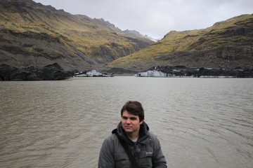 Fototapeta premium Young male tourist posing in front of mountains and icebergs in the background, photo taken in Iceland