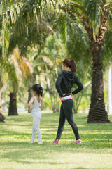 daughter and mother are doing exercises in the summer park