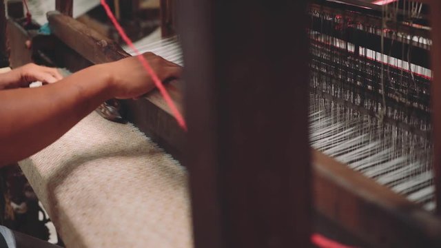 Close up of indonesian man hand weaving fabric with shuttles using foot-treadle loom machine. Shot with Sony a7s and Atomos Ninja Flame in Indonesia